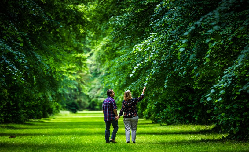 Couple holding hands and looking at leaves at Westonbirt